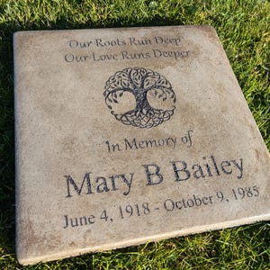 May include: A light brown square concrete memorial stone with a Celtic tree of life design and the inscription "Our Roots Run Deep Our Love Runs Deeper In Memory of Mary B Bailey June 4, 1918 - October 9, 1985".