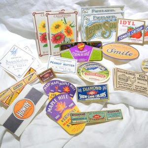 May include: A collection of vintage product labels with various designs and text. Labels include "Calliopsis" with flower illustrations, "Lemon Soda," "Tomato Catsup," and "Peanut Butter." The labels are in various shapes and colors, with a white background.