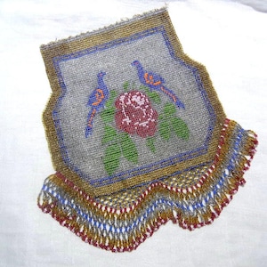 May include: A vintage beaded purse with a floral and bird design. The purse features a gray background with a red rose and two blue and orange birds. The border is gold, and the bottom edge has a colorful fringe.