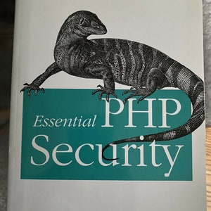 May include: A book titled "Essential PHP Security: A Guide to Building Secure Web Applications" by Chris Shiflett. The cover features a black and white illustration of a lizard on a teal green background with the title in white text.
