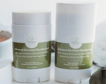 May include: Two white deodorant sticks with green labels that read "Mineral Enriched Deodorant". A white bar of soap and a bowl are in the background. The sticks are 2.6 oz (75ml).
