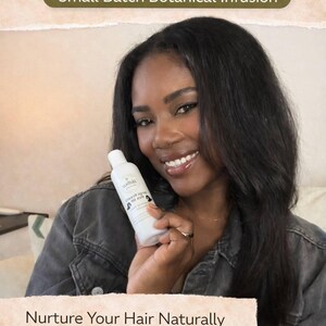 May include: A woman smiles while holding a white bottle of herbal hair oil. The bottle has a label with text. The image includes text that reads "HERBAL HAIR OIL" and "Nurture Your Hair Naturally".