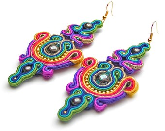 May include: A pair of colorful, rainbow-colored earrings with a gold hook and a dark iridescent stone in the center. The earrings are made of woven thread and beads.