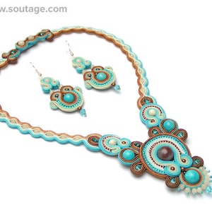 Puede incluir: Un collar y pendientes a juego de cuentas turquesa, marr&oacute;n y blanco. El collar presenta un gran colgante intrincado con una cuenta central marr&oacute;n.