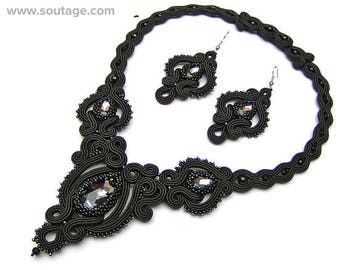 Puede incluir: Un conjunto de collar y pendientes negros con diseños intrincados y acentos de cristal brillante.
