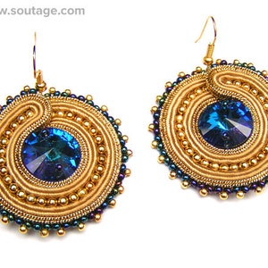 Peut inclure: Boucles d'oreilles dorées et bleues avec un motif en spirale et un cristal bleu au centre. Les boucles d'oreilles sont faites de perles et de fil.