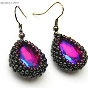 May include: A pair of dangle earrings with black beads and a teardrop-shaped iridescent pink crystal.