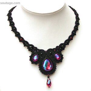 May include: A black beaded necklace with a large, iridescent pink and blue gemstone pendant. The necklace is made of black thread and features a delicate, intricate design.