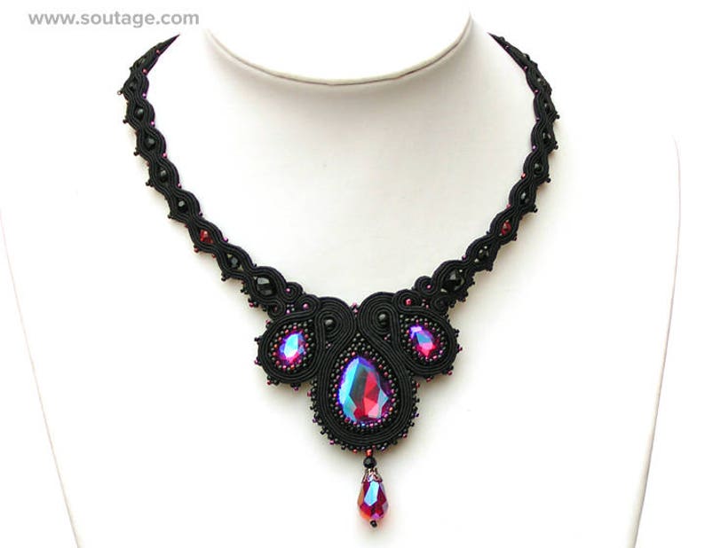 May include: A black beaded necklace with a large, iridescent pink and blue gemstone pendant. The necklace is made of black thread and features a delicate, intricate design.