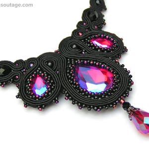 May include: A black beaded necklace with a large, iridescent pink gemstone pendant. The necklace is made of black thread and features a delicate, intricate design.