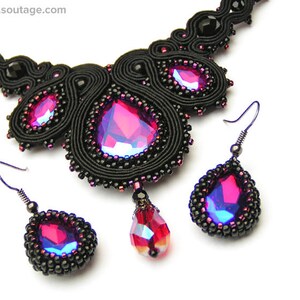 May include: A black beaded necklace and matching earrings with a large, iridescent pink gemstone pendant. The necklace is made of black thread and beads, and the earrings are teardrop shaped.