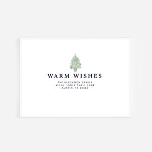May include: A white card with the text "WARM WISHES" in navy blue. A watercolor illustration of a Christmas tree is above the text. Below the text is the family name and address.