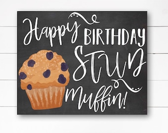 May include: A chalkboard sign with white text that reads "Happy Birthday You Stun Muffin!"  A cartoon blueberry muffin is pictured on the left side of the sign.