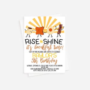 May include: A yellow and orange breakfast-themed birthday invitation with a cartoon illustration of a cup of coffee, toast, a fried egg, and bacon. The text reads "Rise and Shine it's breakfast time!" and "Baylor's 5th Birthday".