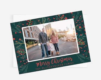 Peut inclure: Une carte de Noël avec un fond vert et des baies rouges. Une famille de quatre personnes est photographiée devant un panorama urbain. Le texte "Merry Christmas" et "The Blankenbaker Family" est imprimé sur la carte.