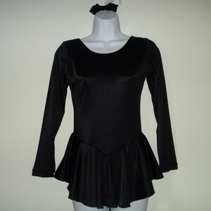 May include: Black long-sleeved leotard with a flared skirt and a matching scrunchie. The leotard has a scoop neckline and a fitted bodice. The skirt flares out from the waist. The scrunchie is on a mannequin head.