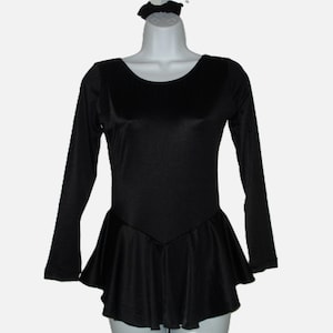 May include: A black long-sleeved leotard with a flared skirt and a matching scrunchie. The leotard has a scoop neckline and a fitted bodice. The skirt flares out from the waist. The scrunchie is at the top of the mannequin head.