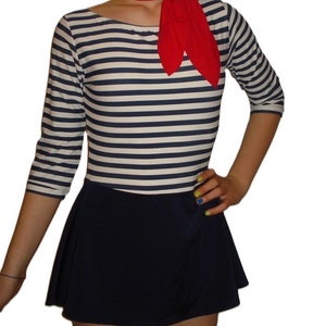 May include: A nautical-themed outfit featuring a striped long-sleeve top in navy and white, paired with a navy skirt. A red scarf is tied around the neck. The outfit is a classic, timeless style.