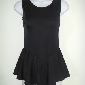 May include: A sleeveless black leotard with a scoop neckline and a flared skirt. The leotard is displayed on a white mannequin. The skirt has a pleated design, adding a touch of elegance to the garment.