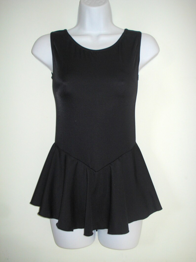 May include: A sleeveless black leotard with a scoop neckline and a flared skirt. The leotard is displayed on a white mannequin. The skirt has a pleated design, adding a touch of elegance to the garment.
