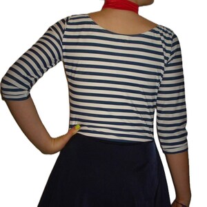 May include: A nautical-themed outfit featuring a navy blue and white striped three-quarter sleeve top and a navy blue skater skirt. A red scarf is worn around the neck.