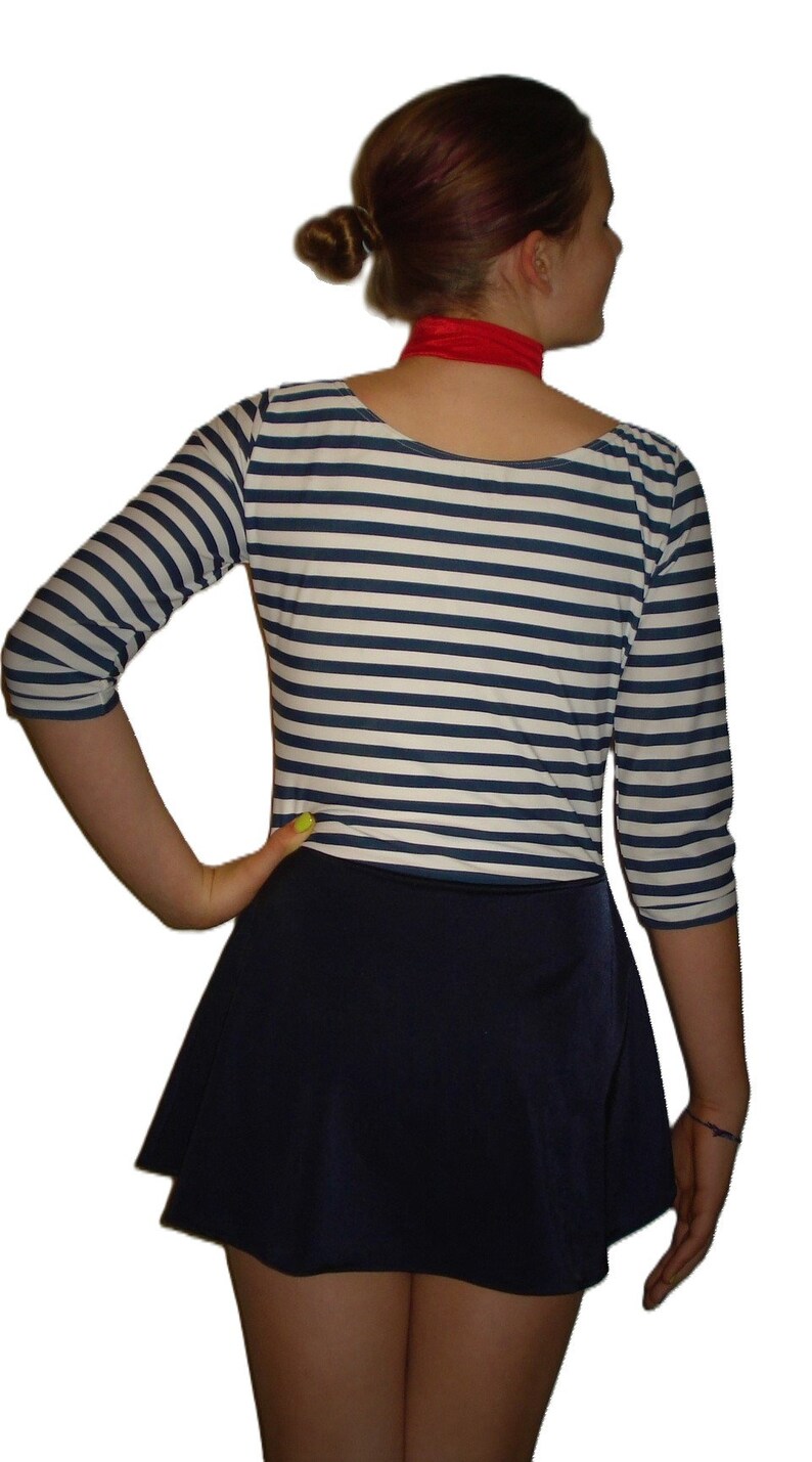 May include: A nautical-themed outfit featuring a navy blue and white striped three-quarter sleeve top and a navy blue skater skirt. A red scarf is worn around the neck.
