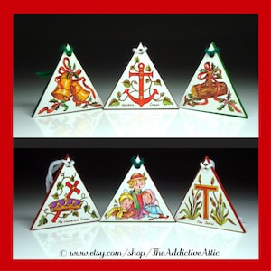 May include: Set of six vintage triangular Christmas ornaments. Each ornament features a different illustration, including bells, an anchor, a log, a crown, children, and a letter "T". The ornaments have green and red accents and are strung with white or green string.