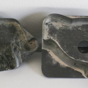 May include: Four vintage metal cookie cutters in the shapes of a bird, a cow, a pig, and a dog. The cutters are made of a dark gray metal and have a slightly worn appearance.