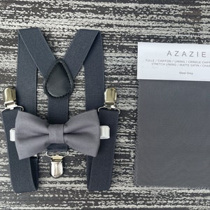 May include: A gray bow tie and suspenders set with a fabric swatch labeled "Steel Grey" and the text "AZAZIE TULLE/CHIFFON/LINING/CRINKLE CHIFFON/MESH STRETCH LINING/MATTE SATIN/CHARMEUSE".