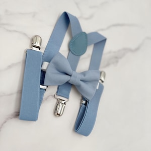 May include: A light blue bow tie and suspenders set. The bow tie is made of a soft fabric and has a classic design. The suspenders are adjustable and have silver clips.