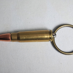 May include: A brass bullet casing keychain with a copper tip and a brass key ring.