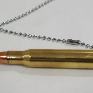 Peut inclure: Un collier avec une douille de balle dorée, une chaîne argentée et un fermoir argenté. La douille de balle mesure environ 5 cm de long.