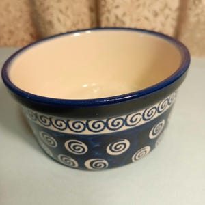 May include: A blue and white ceramic bowl with a swirl pattern. The bowl is empty and has a smooth, glazed finish.