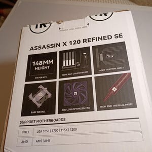 May include: A white box for the Assassin X 120 Refined SE, a computer component. The box features diagrams and text, including "148MM HEIGHT", "AIRFLOW OPTIMIZED FAN", and "HIGH END THERMAL PASTE". It supports Intel and AMD motherboards.