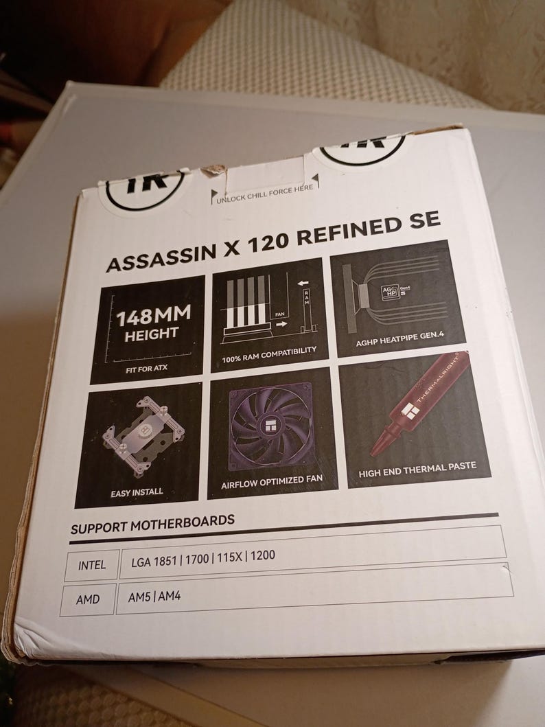 May include: A white box for the Assassin X 120 Refined SE, a computer component. The box features diagrams and text, including "148MM HEIGHT", "AIRFLOW OPTIMIZED FAN", and "HIGH END THERMAL PASTE". It supports Intel and AMD motherboards.