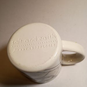 Peut inclure: Mug en c&eacute;ramique cr&egrave;me avec une anse incurv&eacute;e. Le fond du mug porte l'inscription en relief "salt and earth" et "for ANTHROPOLOGIE". Le mug pr&eacute;sente un motif marbr&eacute; gris subtil sur les c&ocirc;t&eacute;s.