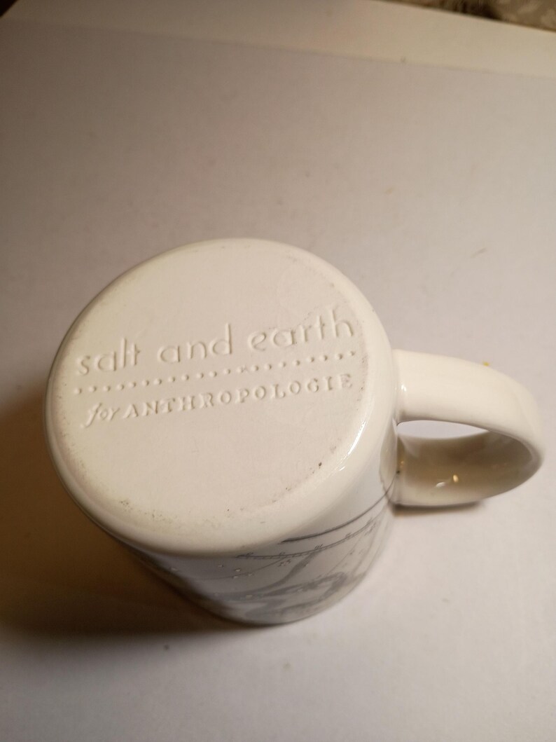 Peut inclure: Mug en c&eacute;ramique cr&egrave;me avec une anse incurv&eacute;e. Le fond du mug porte l'inscription en relief "salt and earth" et "for ANTHROPOLOGIE". Le mug pr&eacute;sente un motif marbr&eacute; gris subtil sur les c&ocirc;t&eacute;s.