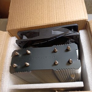 May include: A black Thermalright CPU cooler with a fan, packaged in a cardboard box with foam padding. The cooler has a fin stack design and the brand name is printed on the top.