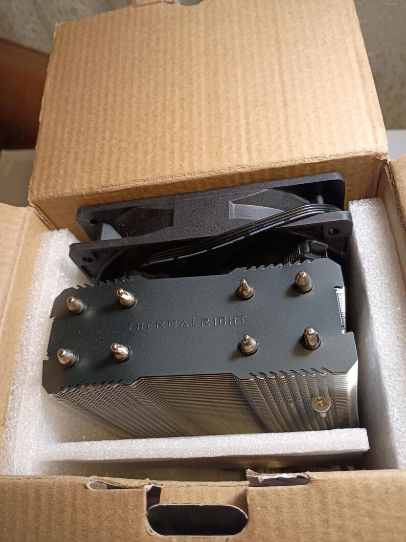 May include: A black Thermalright CPU cooler with a fan, packaged in a cardboard box with foam padding. The cooler has a fin stack design and the brand name is printed on the top.