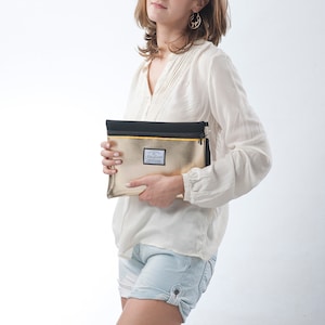 May include: A gold clutch purse with a black zipper and a small black label with the text "DearLove" on it.