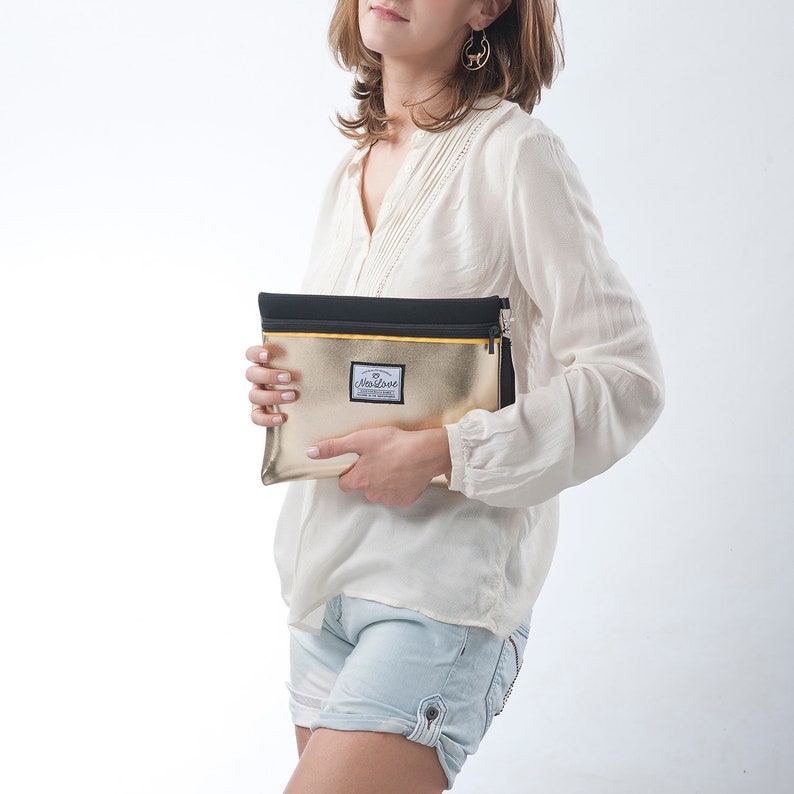 May include: A gold clutch purse with a black zipper and a small black label with the text "DearLove" on it.