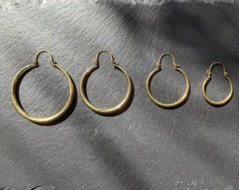 May include: Four gold hoop earrings of different sizes. The earrings are arranged in a row from largest to smallest.