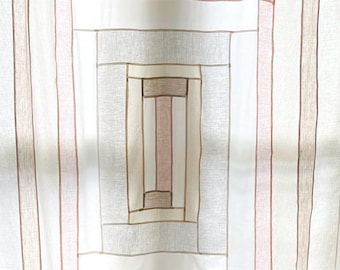 May include: Cream-colored fabric with a geometric design. The pattern features vertical stripes in shades of beige, pink, and brown, with a central rectangular design. The fabric appears to be lightweight and suitable for curtains or other home decor items.