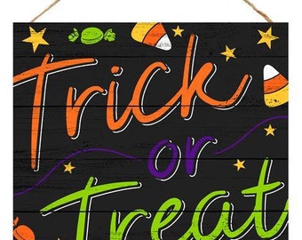 May include: Black wooden sign with the text "Trick or Treat" in colorful letters. The sign has a rope hanger and is decorated with candy corn, candy, and stars.