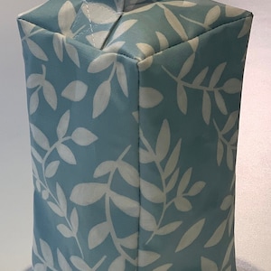 Puede incluir: Un tope de puerta azul claro con un patr&oacute;n de hojas blancas y un asa de tela.