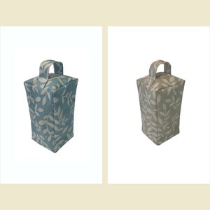 Puede incluir: Dos topes de puerta con un patr&oacute;n de hojas. Uno es azul con hojas blancas y el otro es beige con hojas blancas.