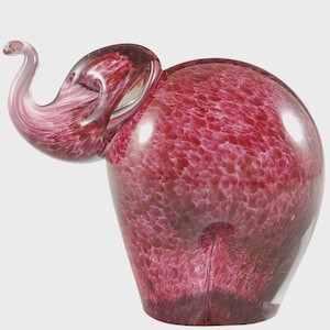 May include: A decorative glass elephant sculpture in shades of pink and red. The elephant has a textured body and a curled trunk. The sculpture is a unique piece of art and a decorative item.