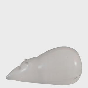 May include: A white ceramic polar bear figurine. The bear is lying down with its head slightly raised, and its body is smooth and rounded. The figurine has small, detailed ears and a pointed snout. The overall design is minimalist and modern.