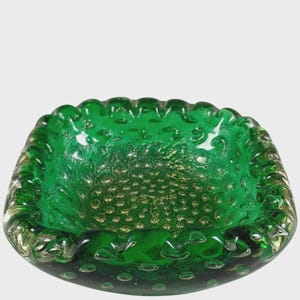 May include: A square-shaped emerald green glass bowl featuring a distinct bullicante technique with numerous trapped air bubbles throughout the thick glass walls. The rim has a scalloped, wavy edge, and the interior base displays a textured pattern.