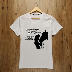 May include: White t-shirt with a black silhouette of a woman and a horse. The text reads "If my horse doesn't like you I probably won't either."